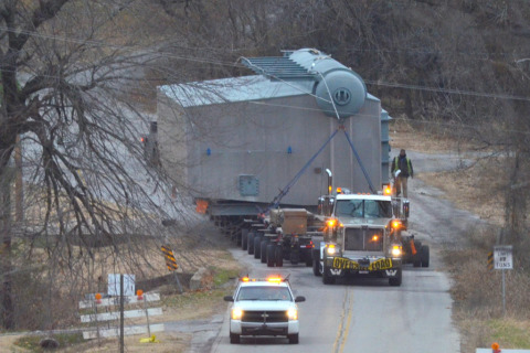A pilot car leads the way for a hydraulic platform flatbed trailer hauling an oversize load