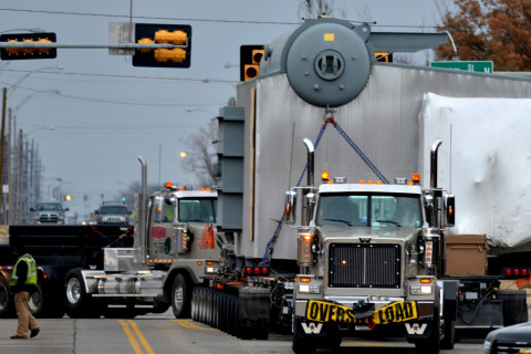 A hydraulic platform flatbed trailer skillfully hauls an oversized load through a busy intersection